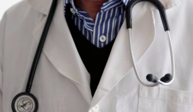 Illustrasjonsfoto hvor en lege står med stetoskop rundt halsen. Han har på seg en hvit frakk og en mørkeblå genser.