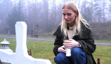 Ung jente med langt, lyst hår sitter på huk ved en grav. Et hvitt kors står i forgrunnen. På graven er det lys og blomster.