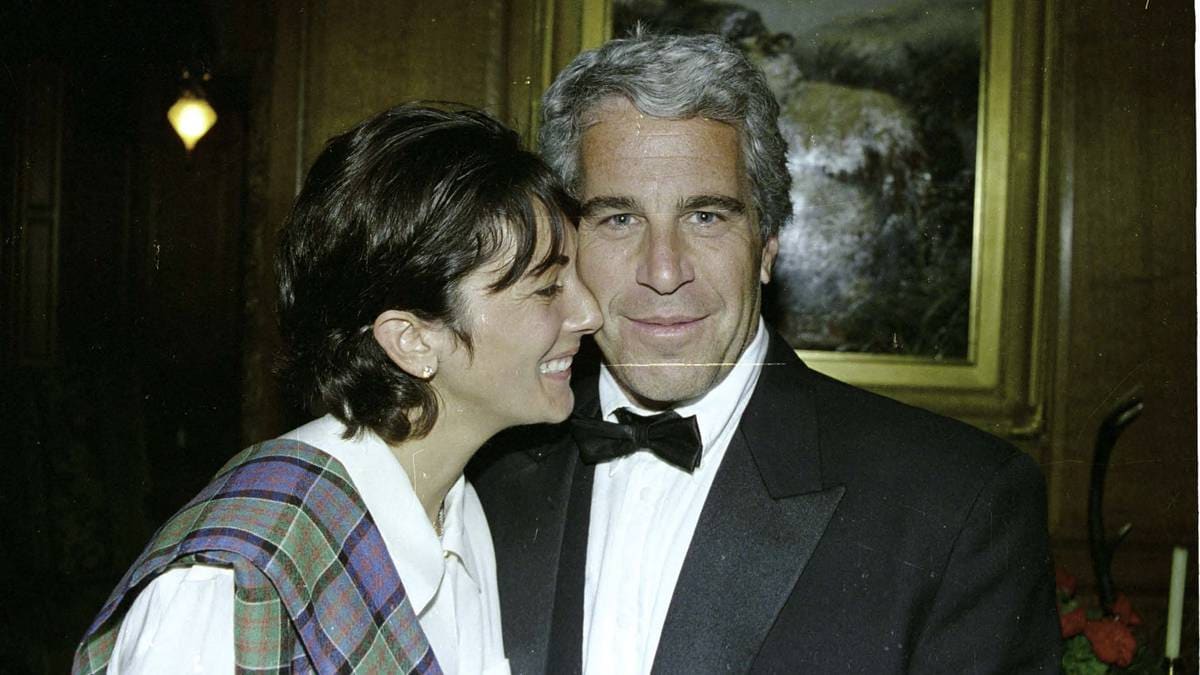 To personer står sammen i en formell setting iført dress og tartansjal. Bildet viser en dekorativ innrammet maleri og trepanel i bakgrunnen. Scenen er lys med en lykt i bakgrunnen som kaster et mykt lys. En etikett i nederste hjørne merket "GOVERNMENT EXHIBIT 321" indikerer bildet som bevis i en sak. (Bildebeskrivelsen er laget av en KI-tjeneste)