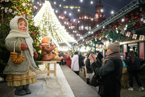 A woman takes pictures of the New Year decorations at Manezhnaya square in Moscow, Russia, Wednesday, Dec. 3, 2025. (AP Photo/Pavel Bednyakov)
