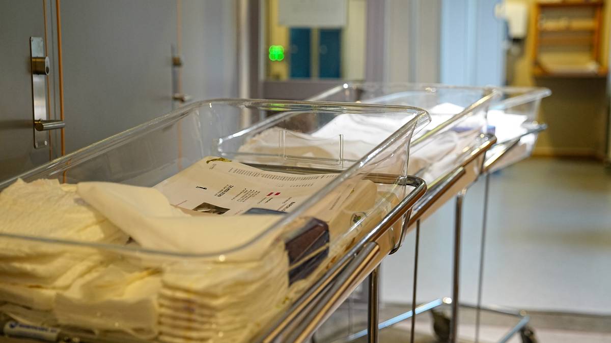 Bildet viser flere klare, plastkasser plassert på traller i et rom som sannsynligvis er en sykehusavdeling. Hver kasse inneholder stabler av berg med tekstiler og papirdokumenter, som kan indikere forberedelser for et medisinsk inngrep. Omgivelsene virker ryddige og profesjonelle, med en dør i bakgrunnen som gir tilgang til et annet rom. Det er et grønt lys i nærheten, som kan signalisere aktivitet eller observasjon i området. (Bildebeskrivelsen er laget av en KI-tjeneste)