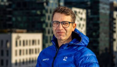 En person iført en blå jakke med logoene til TV 2 og Craft står foran høyhus i urbane omgivelser. Bakgrunnen viser moderne arkitektur med høye bygninger. Bildet er tatt i dagslys, noe som gir skarp belysning. (Bildebeskrivelsen er laget av en KI-tjeneste)