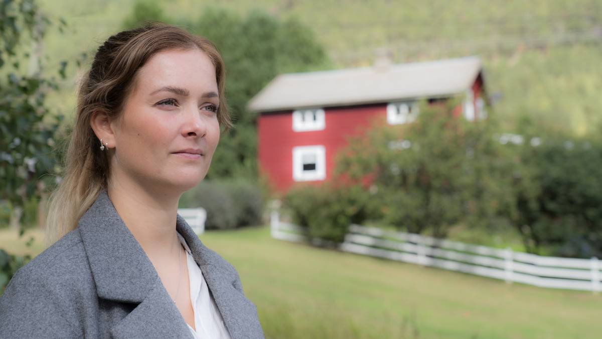 en person som står foran et rødt hus