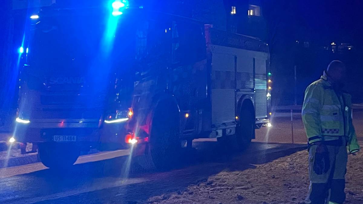 Viser brannbil med blålys og to brannmenn