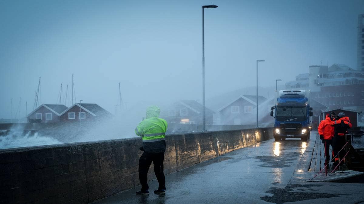 Mann med gul regnjakke i sjøsprøyt på moloen i Bodø