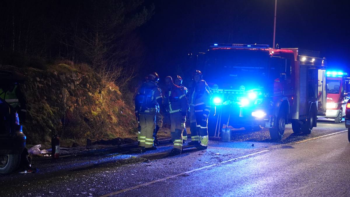 Utrykning etter en bilulykke på en mørk vei. Brannfolk står samlet ved en skadet bil og en brannbil, med blålys på. Flere biler passerer forsiktig forbi hendelsesstedet. Omgivelsene består av trær og veibelysning i bakgrunnen. (Bildebeskrivelsen er laget av en KI-tjeneste)