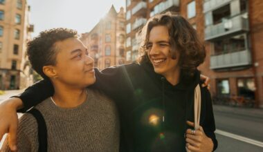 En smilende ung mann holder armen rundt en kamerat i en bygate.