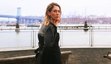 Anna of The North går bortover en vannkant med en lang hengende skinnjakke