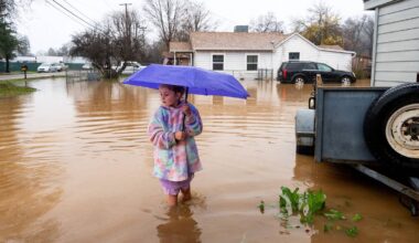 Bildet viser en liten jente med en lilla paraply. Hun står i regnvann opp til leggene utenfor hjemmet sitt i California.