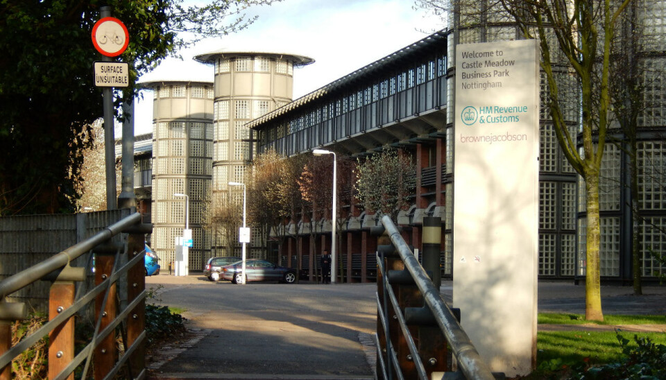 Gangbro fører til moderne kontorbygg med glasstårn og skilt ved gaten