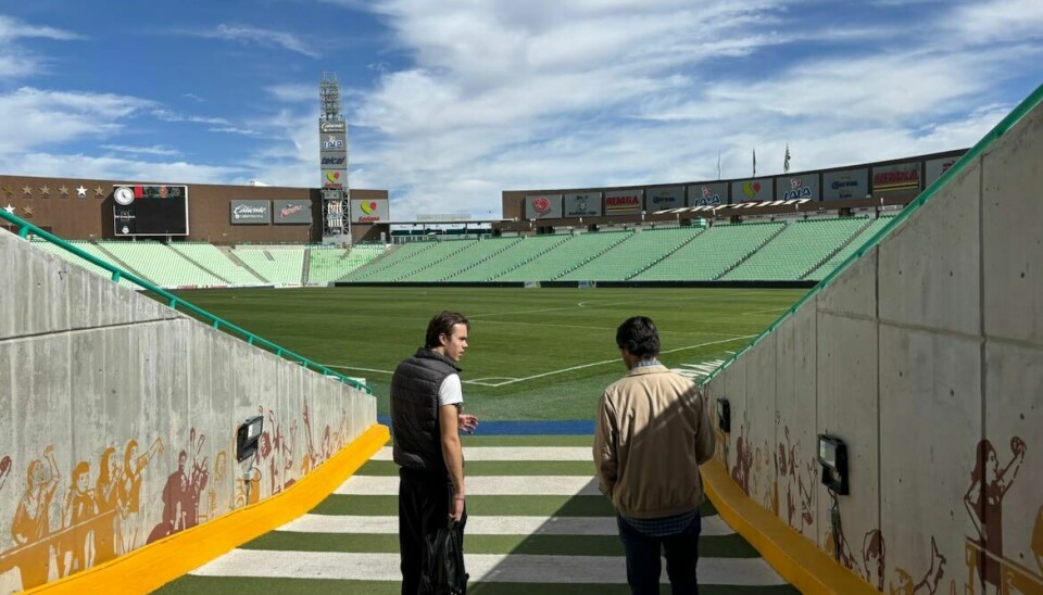 To personer går opp spillertunnelen mot en stor fotballbane på stadion.