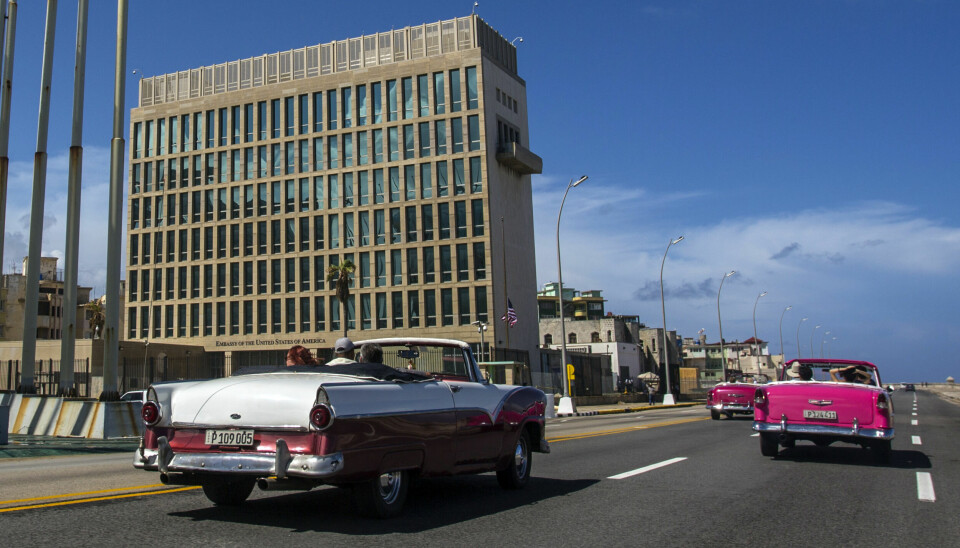 Klassiske cabrioletbiler kjører forbi USAs ambassade langs kystveien i Havana.