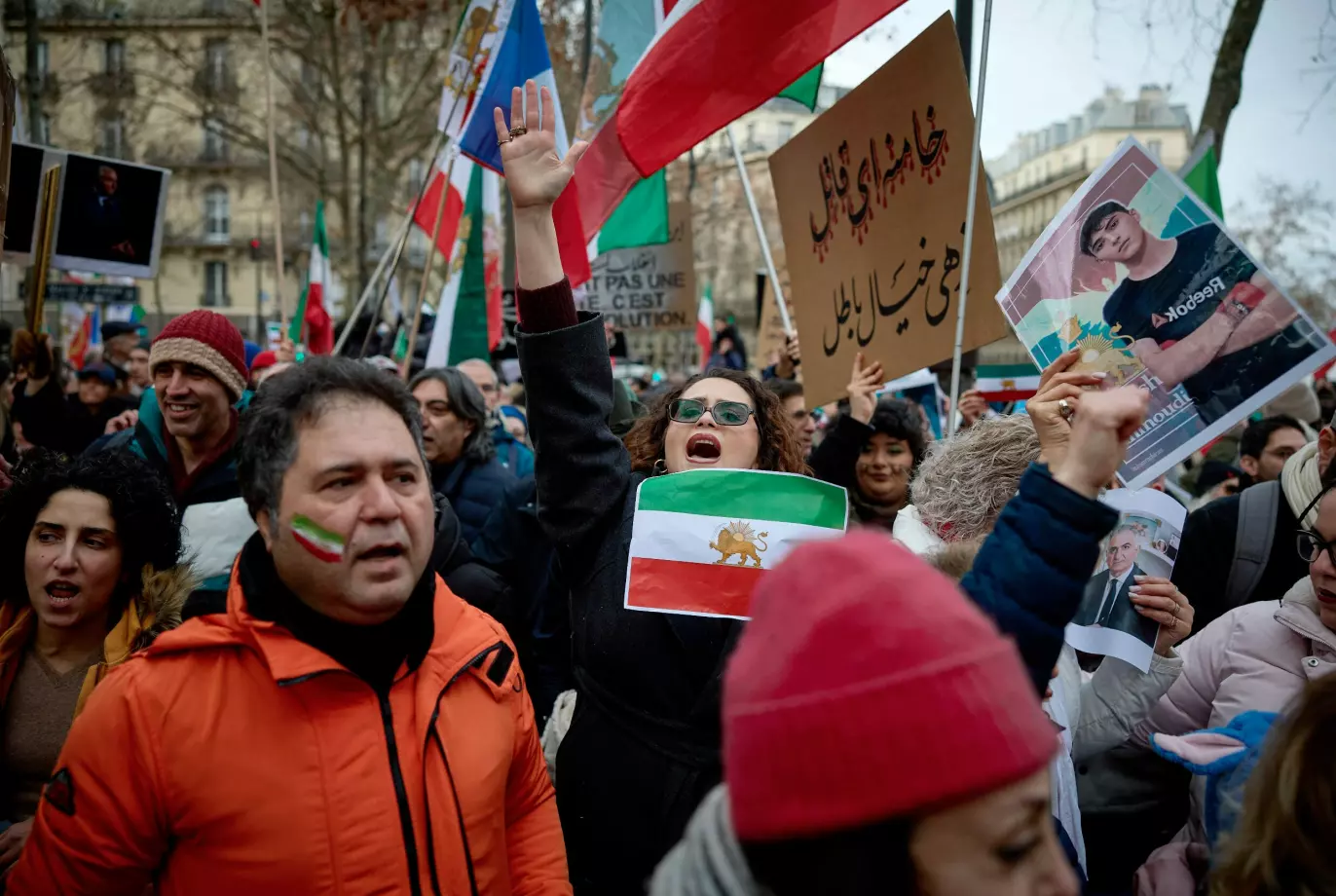 NED MED REGIMET: En kvinne holder opp flagget som representerte Iran fram til den islamske revolusjonen i landet i 1979 under en demonstrasjon i Paris denne uka. Foto: Kiran Ridley / AFP / NTB