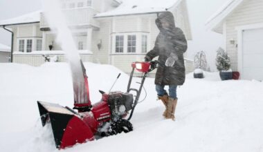Kvinne som måker snø med snøfreser.