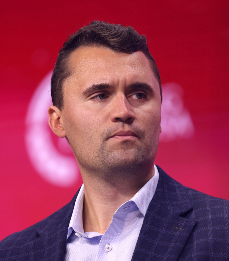 Portrett av Kirk i dress foran rød bakgrunn