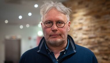 Skjalg Fjellheim står fremfor en murvegg og heisen på Scandic i Alta.