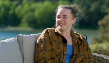 En jente med en rutete skjorte og håret satt opp smiler mot kamera