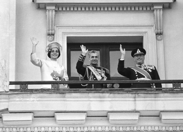 Sjahen av Iran og keiserinne Farah på besøk i Norge, 27. mai 1961, her vinkende fra Slottet med kong Olav til høyre. Sønnen, Reza Pahlavi er født i 1960, men var ikke med på Europa-turen.