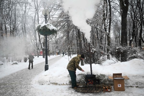 Volunteer Yevgen Gutman cooks baursak, a traditional Central Asian bread, on a potbelly stove at a heating point in a park in Kyiv on January 15, 2026, amid the Russian invasion of Ukraine. (Photo by Sergei GAPON / AFP)