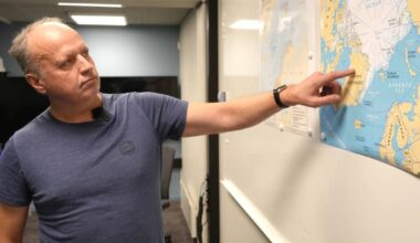 En mann i t-skjorte peker på Grønland på et kart over Arktis.