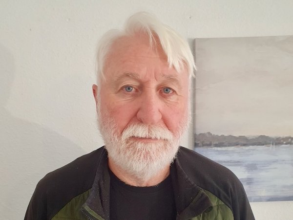 Eldre mann med hvitt hår og skjegg ser inn i kameraet.