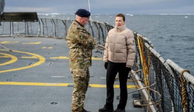 en mann og kvinne som står på et skip med et helikopter i bakgrunnen