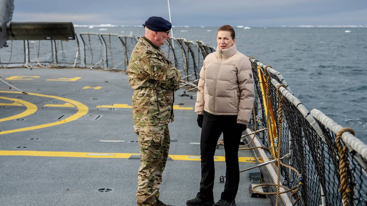 en mann og kvinne som står på et skip med et helikopter i bakgrunnen