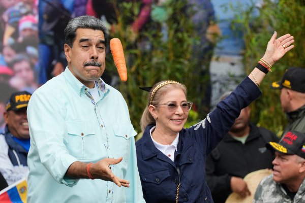President Nicolas Maduro tosses a carrot next to his wife Cilia Flores during a rally marking the anniversary of the Battle of Santa Ines, which took place during Venezuela's 19th-century Federal War, in Caracas, Venezuela, Wednesday, Dec. 10, 2025. (AP Photo/Ariana Cubillos)