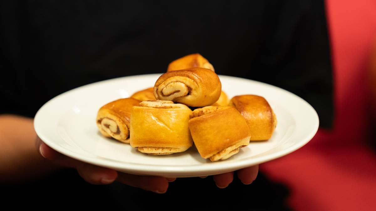 Et fat med kanelgifflar blir holdt opp.