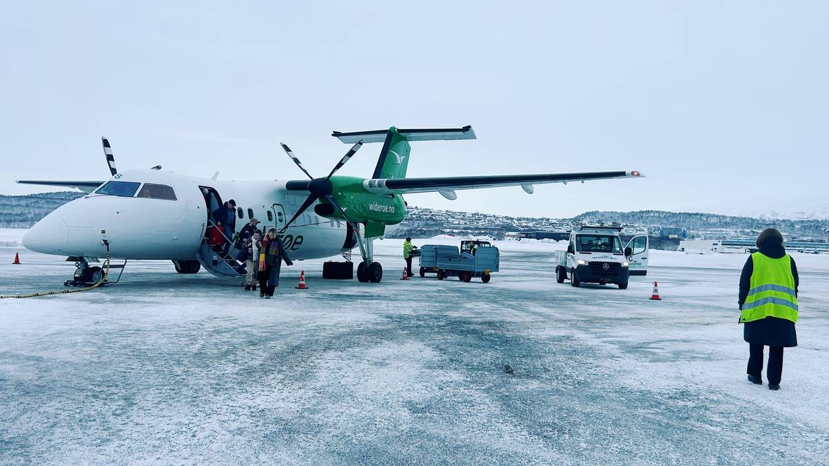 Widerøe fly står på bakken og passasjerer kommer ut på flyplassen i Bodø. En bakkeansatt med gul vest går i forgrunn.