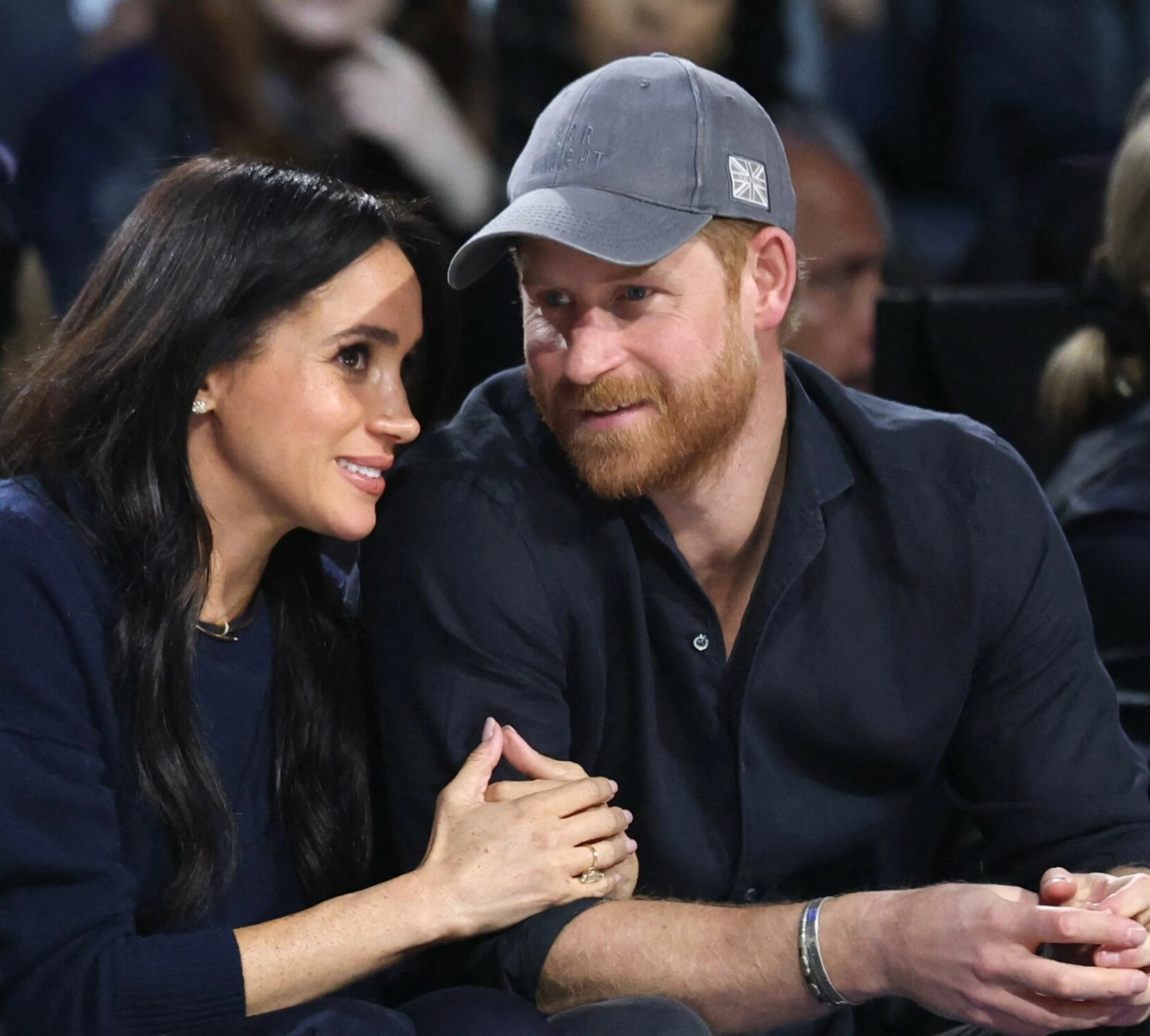 AVSLAPPET KLEDD: Hertuginne Meghan og prins Harry var antrukket i matchende, avslappede antrekk i marineblått, men Meghans smykker hevet utvilsomt glamournivået. Foto: Ronald Martinez/ Getty Images/ AFP/ NTB