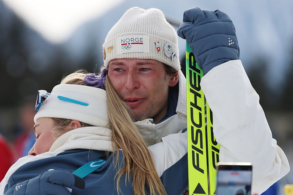 Sturla Holm Lægreid får klem av skiskytterkollega Ingrid Landmark Tandrevold etter medaljeseremonien under dag fire på vinter-OL i Milano Cortina i Antholz-Anterselva i Italia 10. februar 2026 (Harry How/Getty)