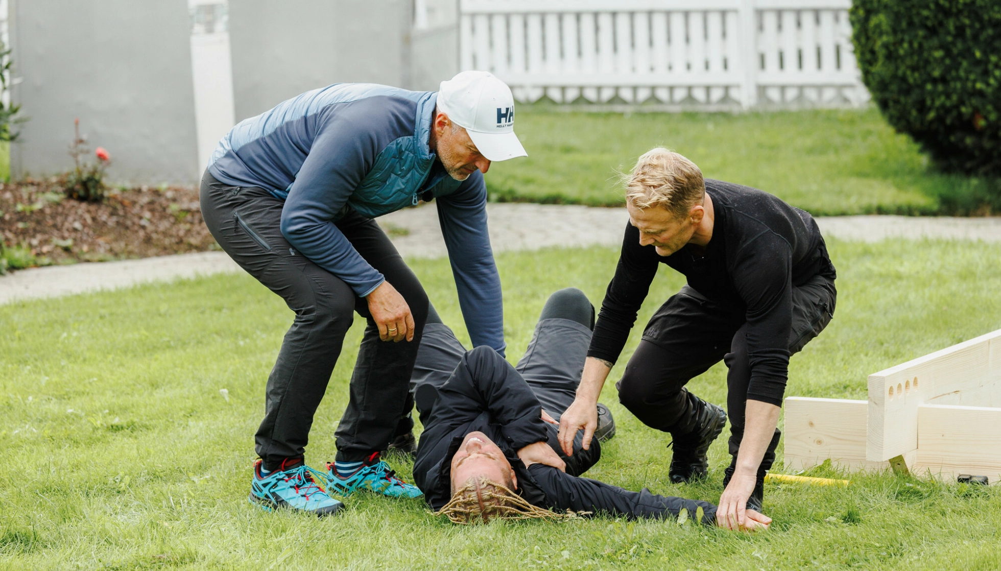 DRAMATISK: Tom Stiansen og Stig André Berge forsøker å hjelpe mens Kevin Lauren vrir seg i smerter. Foto: Haakon Lundkvist