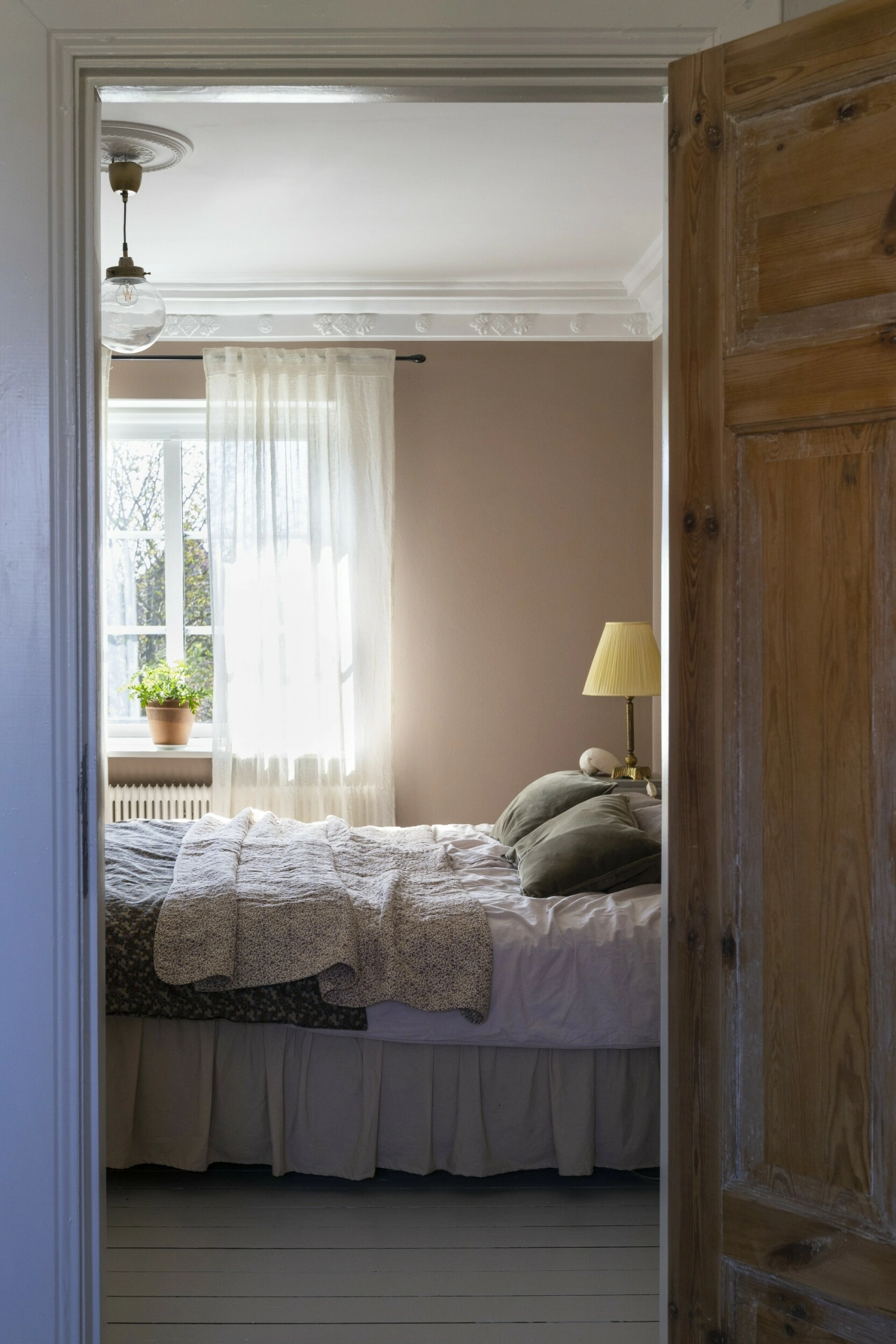 Veggene på soverommet har en
beige-rosa, pudderaktig tone som tar
opp fargen fra teglveggen i rommet ved
siden av. Sengen er dekket med sengekappe og tekstiler i myke nyanser. FOTO: Pernilla Wästberg