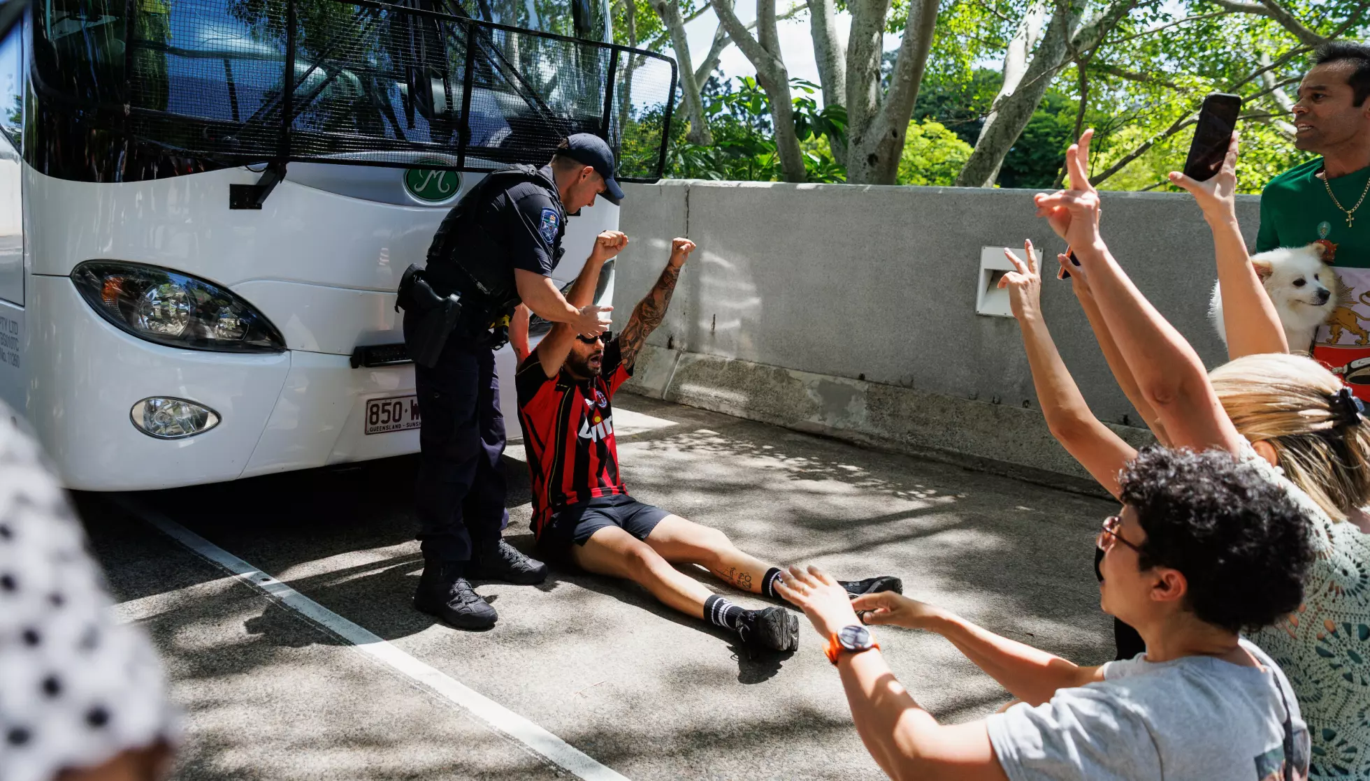 Politiet forsøker å fjerne en demonstrant foran bussen i Gold Coast tirsdag. Foto: Russell Freeman / AAP Image via AP / NTB