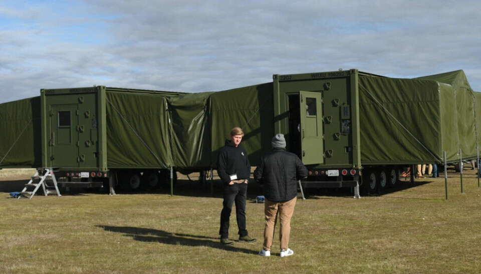 To personer foran grønt mobilt containeranlegg på gresslette