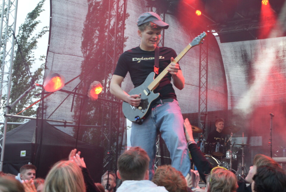 Band spiller live på en utendørsscene foran et publikum i kveldsmørket.