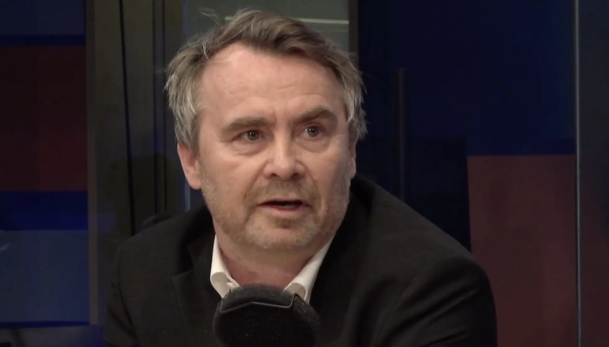 Mann i radiostudio sitter foran en mikrofon og ser til siden