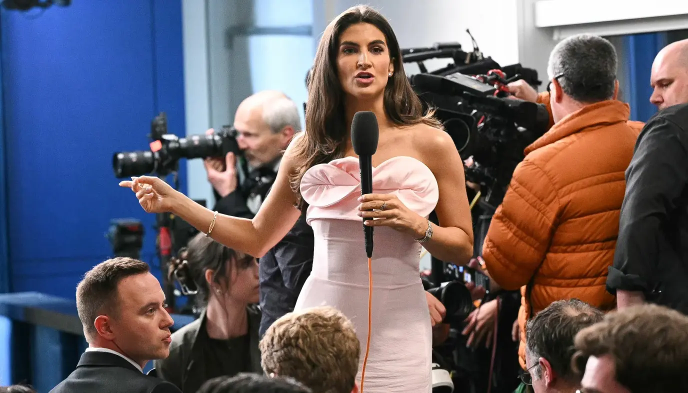 Kaitlan Collins står med mikrofon i Brady Briefing Room mens fotografer og ansatte samler seg rundt henne.