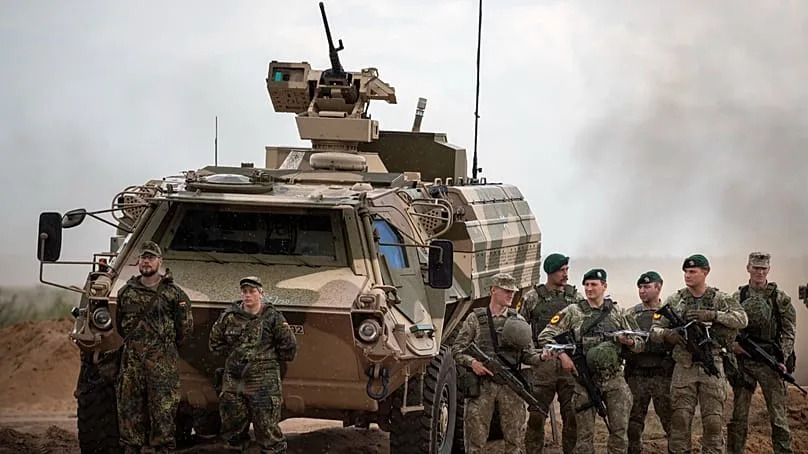 Bundeswehr soldiers stand next to an armoured military vehicle during the “Grand Quadriga 2024” exercise at the Pabradė training area, 29 May 2024.