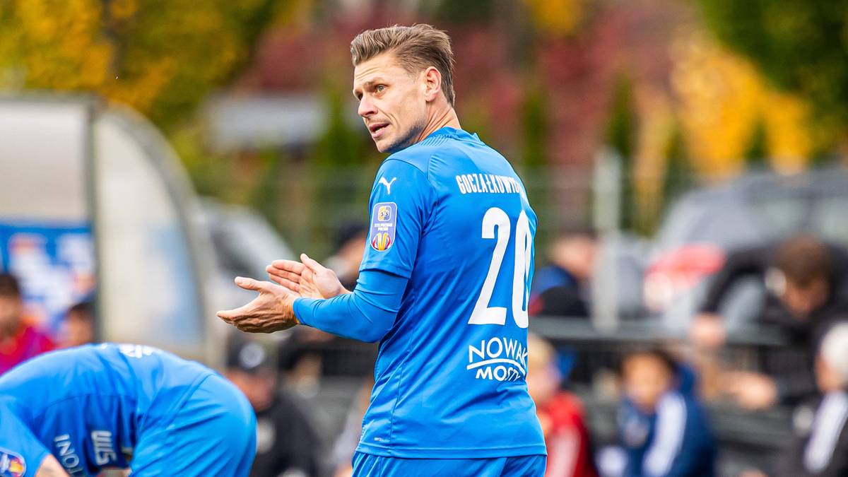 Piłkarz w niebieskiej koszulce z numerem 20 na plecach, patrzący w bok.