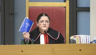 Krystyna Pawłowicz w togach sądowych trzyma książeczkę.