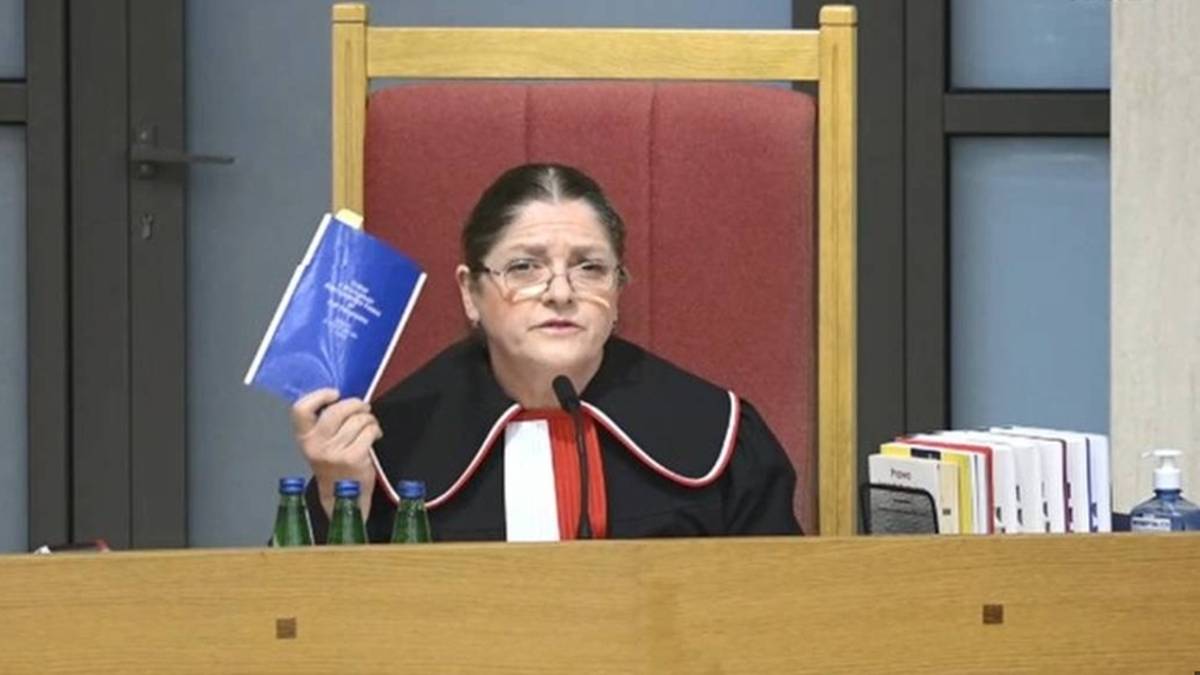 Krystyna Pawłowicz w togach sądowych trzyma książeczkę.