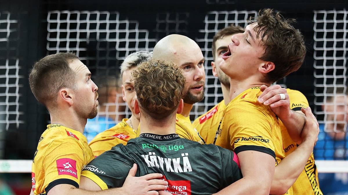 Siatkarze w żółtych strojach zespołowo świętują zwycięstwo, przytulając się do siebie na boisku.