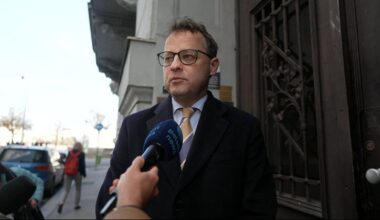 Marcin Romanowski w okularach i ciemnym płaszczu udziela wywiadu dziennikarzowi Polsat News.