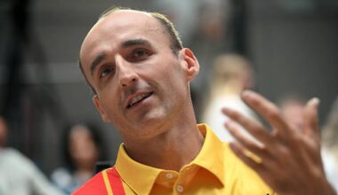 Mężczyzna w żółtej koszulce polo gestykuluje prawą dłonią.