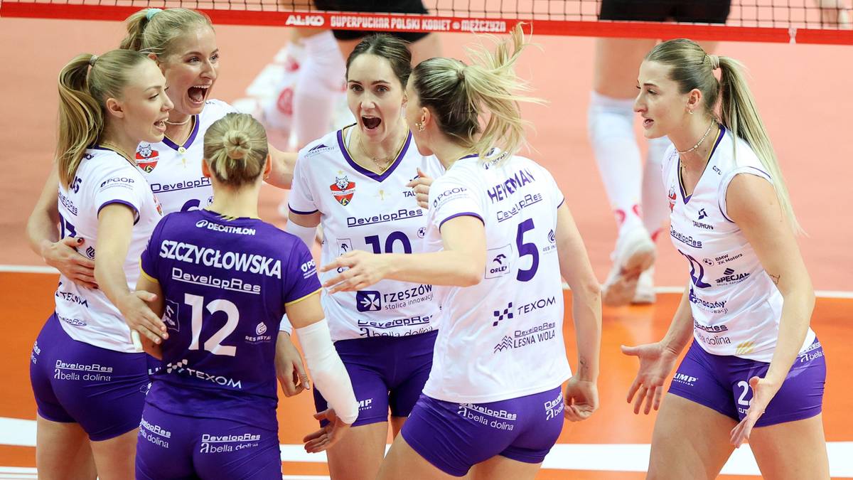 Siatkarki świętujące zwycięstwo na boisku siatkarskim.