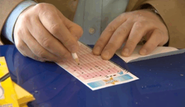 Ręka mężczyzny skreślająca liczby na kuponie Lotto ołówkiem.