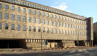 Budynek Sądu Okręgowego w Warszawie, modernistyczna fasada z jasnego kamienia, liczne okna, ulica z chodnikiem przed budynkiem.