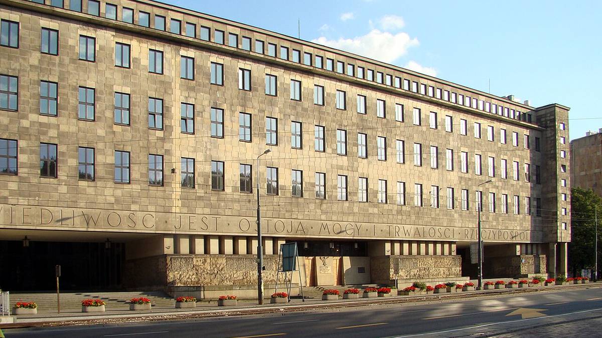 Budynek Sądu Okręgowego w Warszawie, modernistyczna fasada z jasnego kamienia, liczne okna, ulica z chodnikiem przed budynkiem.